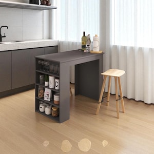Op de afbeelding: Een modern grijs keukeneiland met een ingebouwde wijnrek en planken. Het eiland heeft een aanrecht met flessen en een houten kruk. De keuken heeft een spoelbak, kasten en een raam met witte gordijnen. De vloer is licht hout.