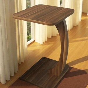 Pu&ograve; includere: Un tavolino in legno con piano quadrato e gamba curva. Il tavolo &egrave; in legno marrone scuro e ha una base rettangolare. Il tavolo &egrave; alto circa 61 cm.