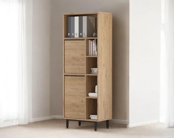May include: A tall, light brown wooden cabinet with black legs. The cabinet has two doors, open shelving, and a top section for storage. The cabinet is filled with books, binders, and decorative items. The cabinet is against a white wall.