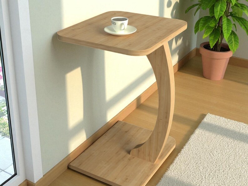 Pu&ograve; includere: Un tavolino in legno chiaro con piano quadrato e gamba curva. Una tazza e un piattino bianchi sono appoggiati sul tavolo. Il tavolo &egrave; vicino a un muro e a una finestra, con una pianta in vaso sullo sfondo.
