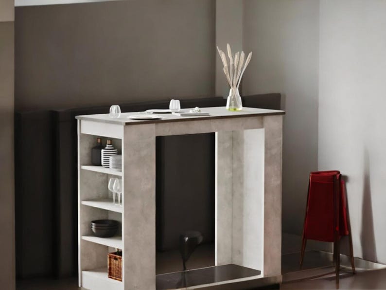 May include: A modern, light gray and white kitchen island with open shelving. The island has a dark countertop and a built-in shelf for storage. A red chair is next to the island. A vase with decorative stems sits on the countertop.