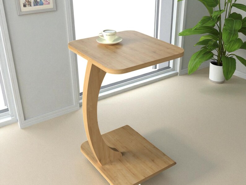 Pu&ograve; includere: Un tavolino in legno chiaro con piano quadrato e gamba curva. Una tazzina da t&egrave; e un piattino sono appoggiati sul tavolo. Il tavolo &egrave; alto circa 61 cm.