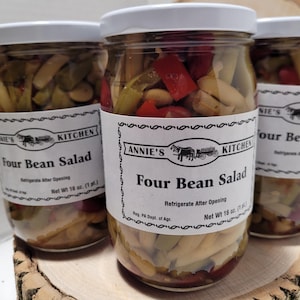 May include: Three glass jars filled with four bean salad. The jars have white lids and labels that say "Annie's Kitchen Four Bean Salad" and "Refrigerate After Opening". The labels also include the net weight of 16 oz (1 pt).