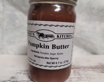May include: A glass jar of pumpkin butter with a white label featuring a horse-drawn carriage illustration. The label reads "Bonnie's Kitchen Pumpkin Butter" with ingredients listed. Net weight is 9.7 oz.
