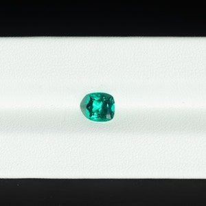 May include: A vibrant green emerald gemstone displayed on a white background.