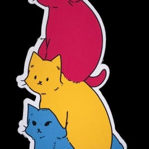以下が含まれることがあります： 3匹の猫が縦に重なったイラストのダイカットステッカー。一番上の猫はマゼンタ、真ん中の猫は黄色、一番下の猫は青色です。それぞれの猫には、目、鼻、ひげがシンプルな黒い線で描かれており、白い縁取りが施されています。