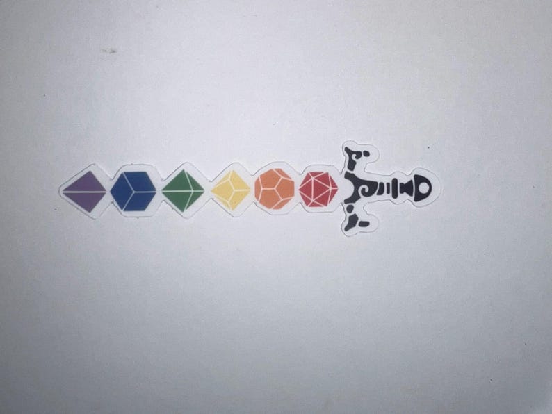 Op de afbeelding: Een sticker met een zwaardontwerp waarbij het lemmet bestaat uit zes veelkleurige veelvlakdobbelstenen op een rij, waaronder paars, blauw, groen, geel, oranje en rood, bevestigd aan een zwart, sierlijk en gestileerd zwaardheft.