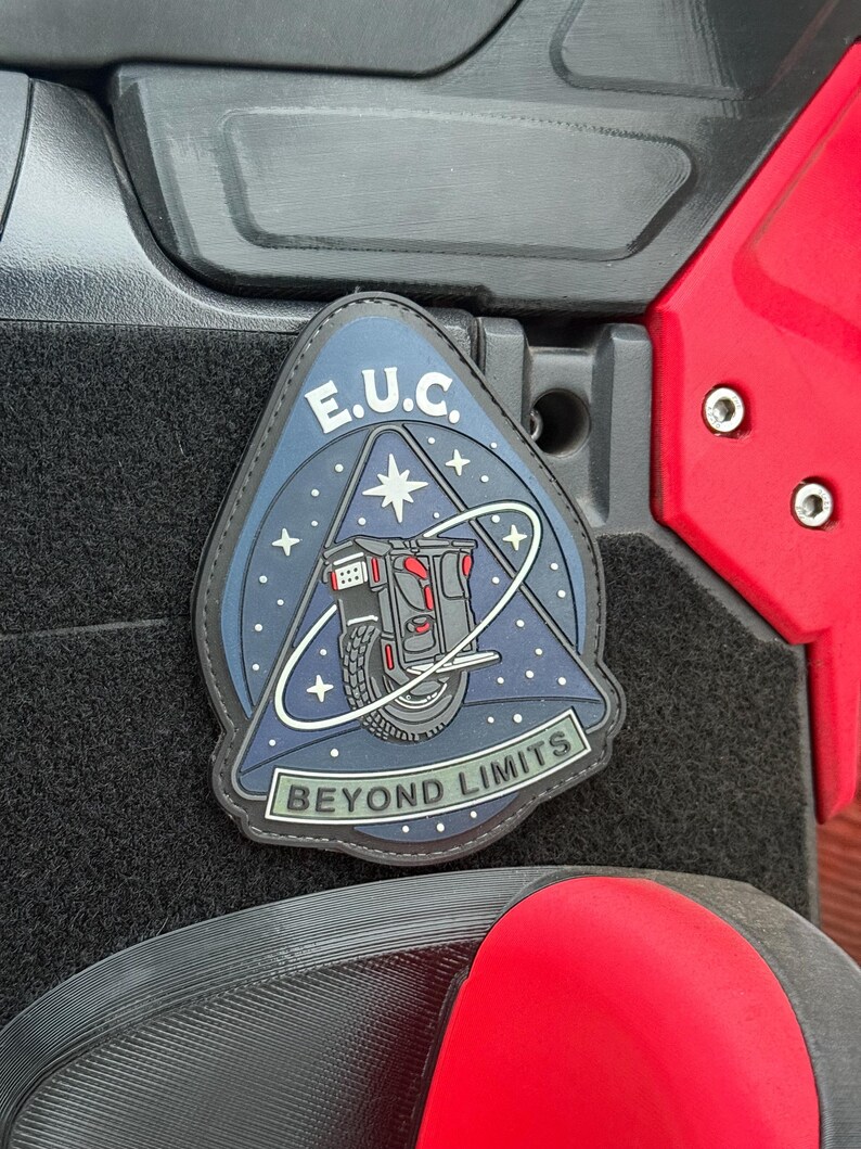 Pode incluir: Um patch com um design azul, preto e branco com o texto "E.U.C." e "BEYOND LIMITS". O patch retrata um ve&iacute;culo futurista com uma roda, contra um fundo de c&eacute;u estrelado.