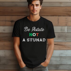 May include: A black t-shirt with the text "Be Astute Not A Stunad" in white with green and red accents.