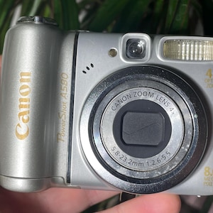 以下が含まれることがあります： シルバーのCanon PowerShot A580デジタルカメラ。Canonズームレンズ、8.0メガピクセル、4倍光学ズームを搭載。レンズのサイズは5.8〜23.2mmです。