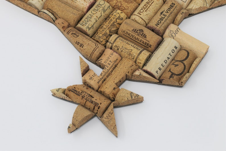 May include: A close-up of a cork star made from wine corks. The corks are arranged in a star shape and have various labels and text, including "PREDATOR", "NOBLE VINES", "DONOVAN-PARKE", "FERRARI-CARINO", and "CALLAWAY".