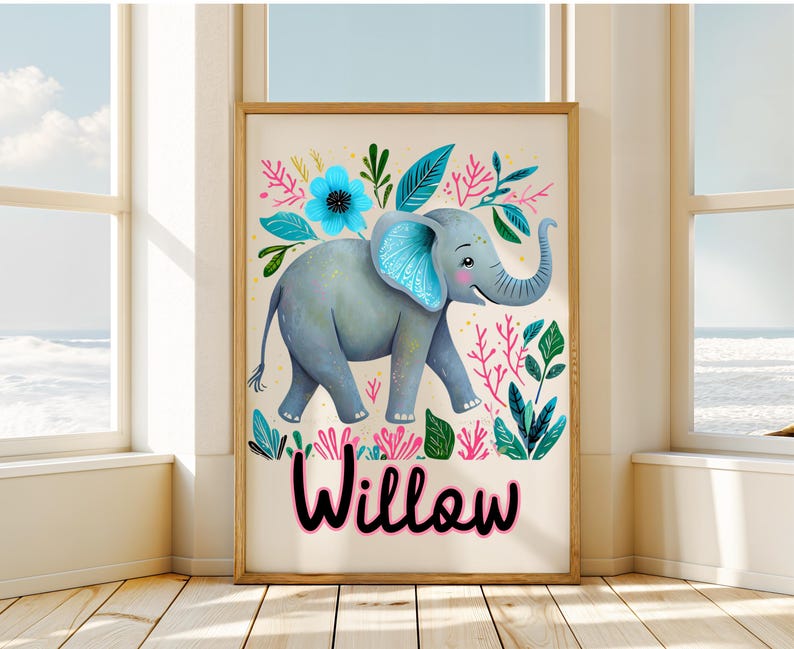 Puede incluir: Un cuadro enmarcado con un elefante gris con detalles azules, rodeado de ilustraciones florales y de hojas coloridas. El nombre "Willow" est&aacute; escrito en rosa. La obra de arte se exhibe en una habitaci&oacute;n con luz natural.