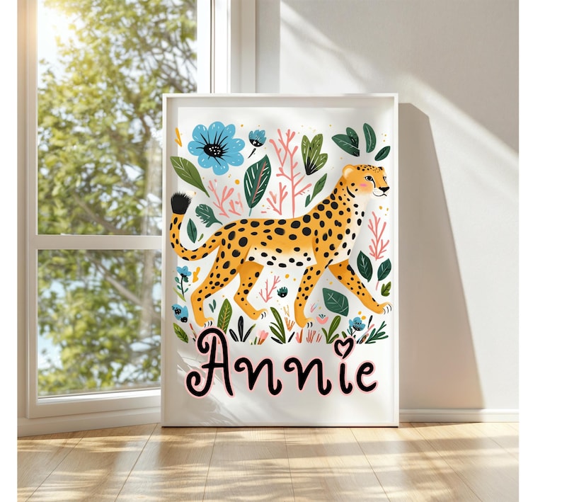 Puede incluir: Un estampado art&iacute;stico enmarcado que presenta un guepardo estilizado con manchas naranjas, caminando entre flores y follaje colorido. El nombre "Annie" est&aacute; escrito en cursiva en la parte inferior. La obra tiene un borde blanco.