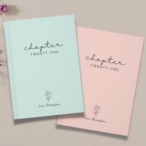May include: Two hardcover journals, one mint green and one pink, are displayed. The cover of each journal features the word "chapter" in a handwritten font, followed by "TWENTY ONE". A small floral illustration and a name are below the text.