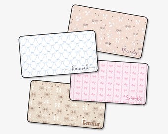 May include: A collection of rectangular mouse pads with bow and heart patterns in various colors. One pad has a blue bow pattern with the name "hannah". Other pads feature names "Mandy", "Brooke", and "Emma".