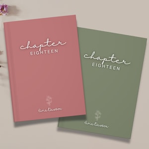 May include: Two hardcover journals, one dusty rose and one sage green, are displayed. Each journal features the words "chapter EIGHTEEN" in a script font, along with the name "Aria Dawson" and a small floral illustration. The journals are on a neutral background.