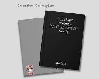 May include: Black notebook with the text "NOTES FROM meetings THAT COULD HAVE BEEN emails" and the name "Madison" printed in white. The notebook is open to reveal a gray page with a cartoon illustration of a cat wearing a pink bandana.