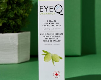 Pode incluir: Um tubo branco de creme para os olhos reafirmante de ameixa kakadu EyeQ Organics. O tubo tem um design de folhas verdes e o texto "Hidratante - Anti-rugas" e "Crème Raffermissante Biologique Pour Les Yeux À La Prune De Kakadu Hydratante - antirides". O tubo é de 0,5 fl. oz. e feito no Canadá.