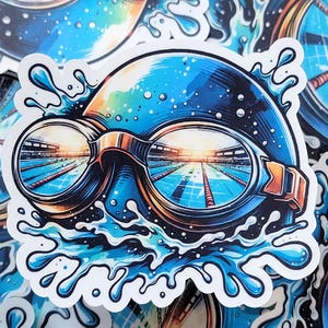May include: A sticker featuring a swimmer's goggles and cap with a pool reflected in the lenses. The design incorporates blue, orange, and white colors, with water splashes around the goggles. The sticker has a glossy finish and is suitable for various surfaces.