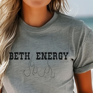 May include: A gray t-shirt with the text "BETH ENERGY" in black lettering with a flame design underneath.