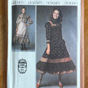 May include: A Simplicity 8728 sewing pattern envelope for a size 12 miss dress. The cover features two illustrations of dresses by Gunne Sax, showcasing long-sleeved, mid-calf length designs with ruffled hems, square necklines, and patterned fabric.