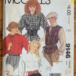 May include: A vintage McCall's sewing pattern featuring illustrations of women's shirts and tops. The cover displays a black and white plaid shirt, a red shirt, and a white shirt. The pattern number is 9146, with a bust size of 32 1/2 inches.