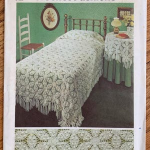 May include: Crochet pattern Simplicity 5543 for a bedspread and table runner. The pattern shows a white crocheted bedspread on a bed with a white crocheted table runner on a table. The pattern is for one size.