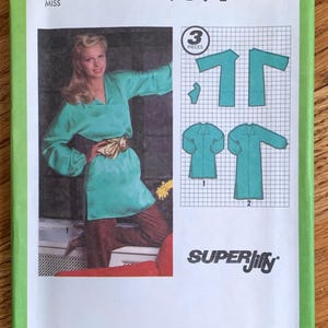 May include: Simplicity sewing pattern number 9191 for a tunic top. The pattern is for size 10 miss and includes three pieces. The pattern shows a woman wearing the tunic top with brown pants.