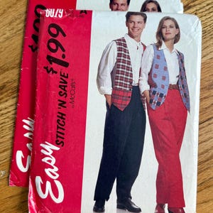 May include: Two McCall's Easy Stitch 'N Save sewing pattern envelopes, number 6079, featuring illustrations of vests, white shirts, and trousers. The red and white packaging displays the pattern number, size ranges, and the McCall's brand name.