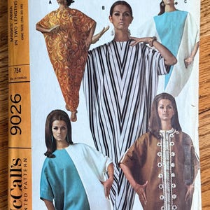 May include: A vintage McCall's 9026 sewing pattern envelope featuring illustrations of four different tunic-style garments. The designs include an orange swirl print, a black and white vertical stripe, a blue and white color block, and a brown tunic with white trim.