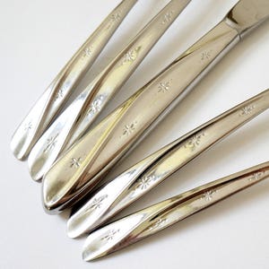 May include: Five silver-toned, star-shaped patterned, flatware knives with twisted handles.