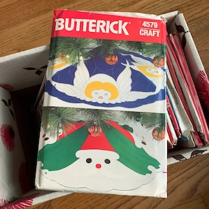 May include: A Butterick craft pattern, featuring a Christmas angel and Santa Claus design. The pattern is labeled "4579" and is in a box with other patterns. The cover art includes green, red, white, and blue colors.