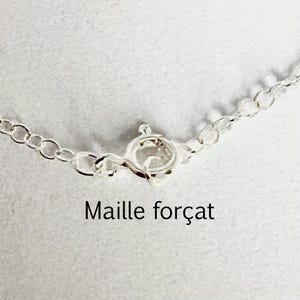 Può includere: Primo piano di una chiusura e catena di collana in argento. Le maglie della catena sono piccole e circolari. La chiusura è di tipo ad anello a molla. Il testo "Maille forçat" è stampato sotto.