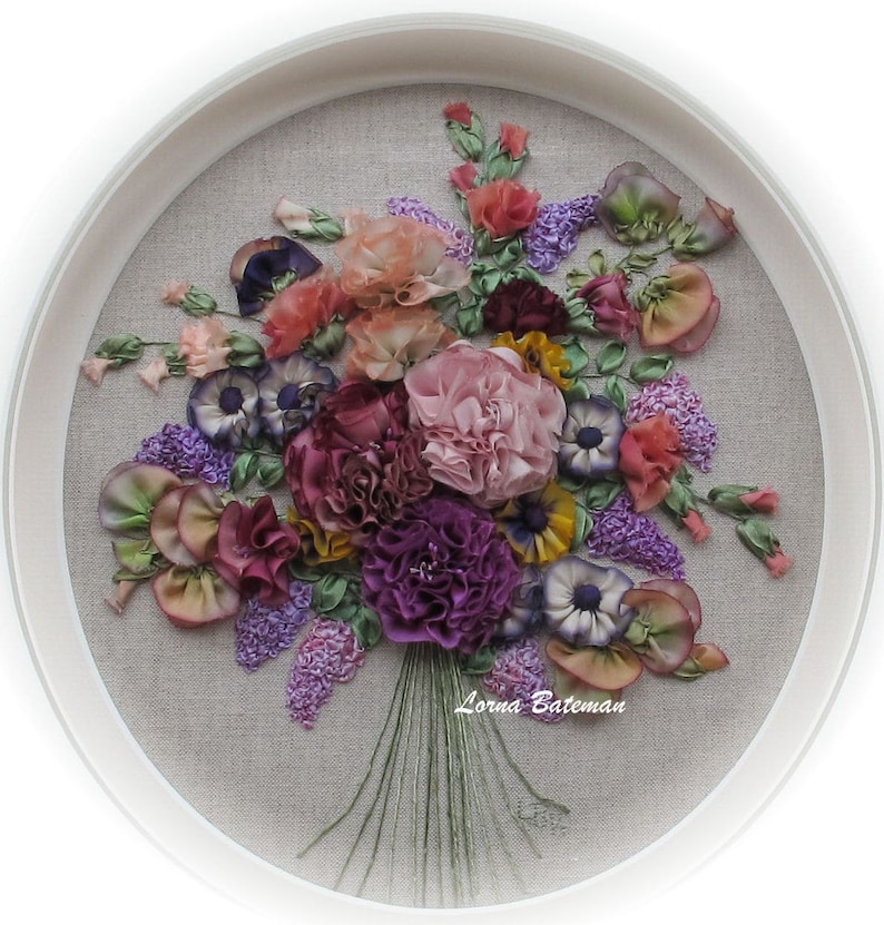 May include: A framed embroidery of a colorful silk ribbon bouquet with pink, purple, and yellow flowers. The artist's signature, "Lorna Bateman", is visible in the bottom right corner.