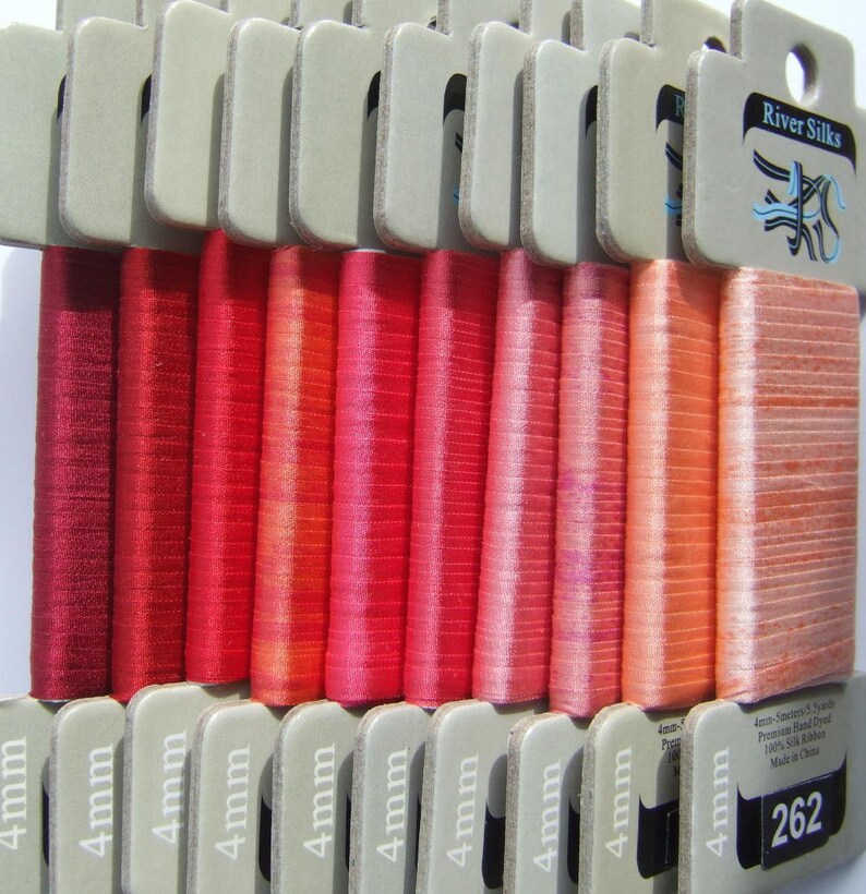Puede incluir: Una colecci&oacute;n de 14 carretes de cinta de seda de 4 mm de ancho en tonos de rojo, naranja y rosa. Los carretes est&aacute;n etiquetados con "4 mm" y el embalaje incluye el texto "River Silks 4 mm-Satin/Satin 5 yards Premium Hand Dyed 100% Silk Ribbon Made in China 262".