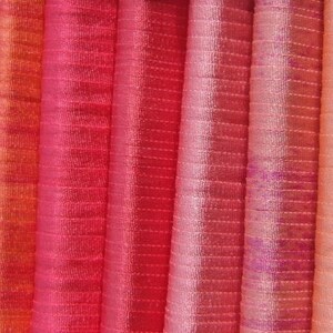 Puede incluir: Una colecci&oacute;n de muestras de tela en varios tonos de rojo, naranja y rosa. La tela tiene un sutil patr&oacute;n a rayas.