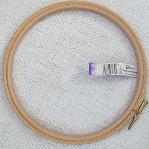 May include: A wooden embroidery hoop with a screw tightening mechanism. The hoop is 6 inches in diameter and is labeled "Elbesee Embroidery Hoop Made in UK".