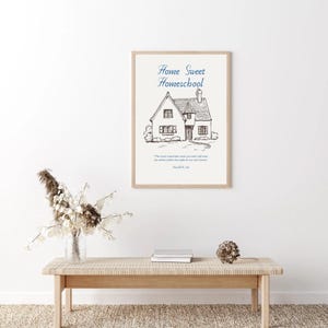 May include: A framed print with the words "Home Sweet Homeschool" above a detailed sketch of a house. The print includes a quote and the name "Harold B. Lee" at the bottom. The frame is a light wood color.