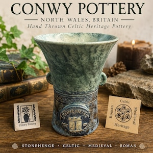May include: A hand-thrown, green and blue pottery vase with the text "CONWY POTTERY" and "STONEHENGE" on the base. The vase has a flared top and two small handles. The image also includes small tags with text and a lit candle.