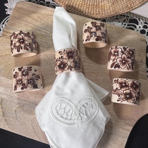 May include: A white ceramic mug with a black handle and the text "But First, Coffee" in a handwritten style. The mug is on a white surface. The mug is approximately 4 inches tall.