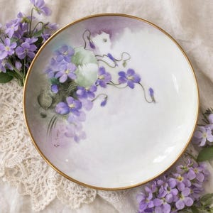 Puede incluir: Juego de tres tazas de cerámica color crema con esmalte moteado. Cada taza presenta un diseño floral pintado a mano en tonos azules, verdes y amarillos. Las tazas tienen una forma simple y redondeada, con asa.