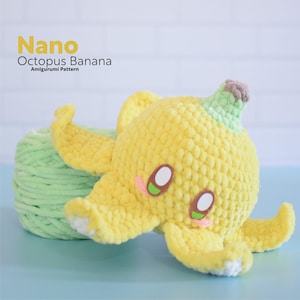 May include: A yellow crocheted octopus shaped like a banana with green crocheted stem. The octopus has two large eyes with white pupils and green irises. The octopus is sitting on a ball of green yarn.