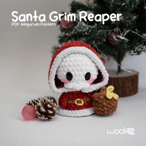 Puede incluir: Un juguete amigurumi de crochet de Santa Claus, vestido con un traje rojo y blanco, con barba blanca y cinturón negro. Está sosteniendo un cono de pino marrón en su mano derecha. El juguete está sentado sobre una superficie blanca frente a un árbol de Navidad.