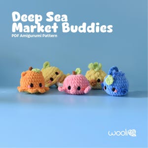 May include: Six crocheted amigurumi sea creatures in shades of orange, yellow, pink, and blue. Each has black eyes and green accents. The text "Deep Sea Market Buddies" is displayed above the creatures, with "PDF Amigurumi Pattern" below.