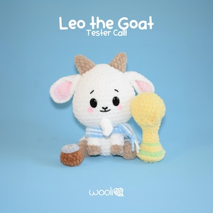 Op de afbeelding: Een wit gebreid knuffeldier in de vorm van een geit met bruine oren en een blauw-wit gestreepte sjaal. De geit houdt een gele gebreide trofee vast. De tekst "Leo the Goat Tester Call!" staat boven de geit.