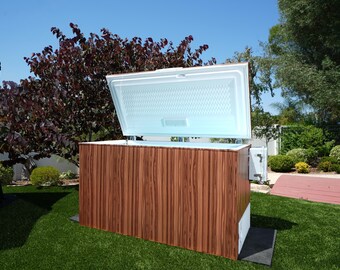 May include: A wooden chest freezer with the lid open, revealing a white interior. The freezer is sitting on a green lawn in front of a house.