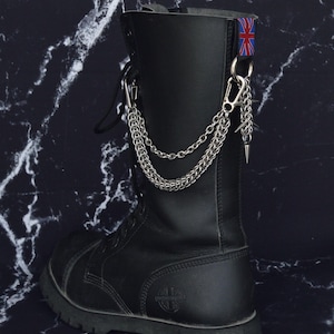 May include: Black leather combat boot with silver chain and spike accents. A small Union Jack flag is attached to the top of the boot. The boot has a thick sole and a round toe.