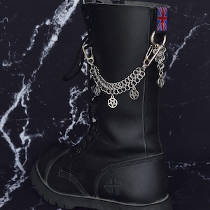 May include: Black leather combat boot with silver chain and pentagram charms. A small Union Jack flag is attached to the top of the boot. The boot has a thick sole and is laced up the front.