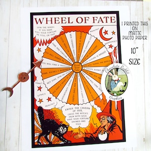 May include: A vintage-style wheel of fate fortune teller print featuring a black cat and a witch. The wheel has a colourful design with orange, yellow, and red colours. The text on the wheel reads "Wheel of Fate" and "Read Your Fate". The print is 10 inches in size and printed on matte photo paper.