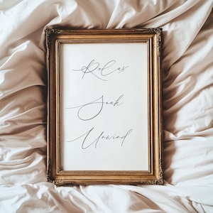 May include: A framed print with the words "Relax, Soak, Unwind" in elegant cursive script. The frame is gold-colored with ornate detailing. The print is displayed on a white background.